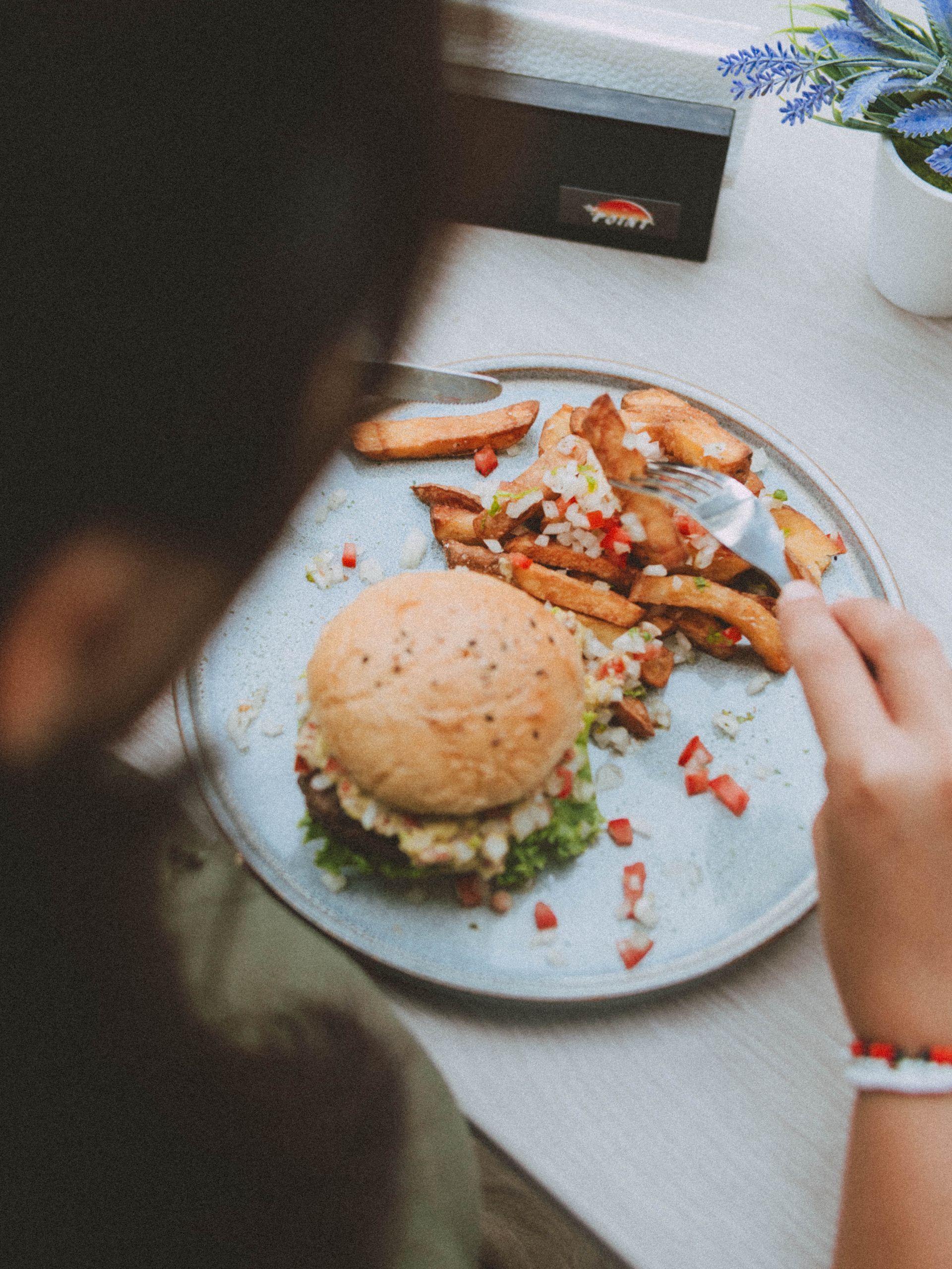 A person is eating a hamburger and french fries on a plate.