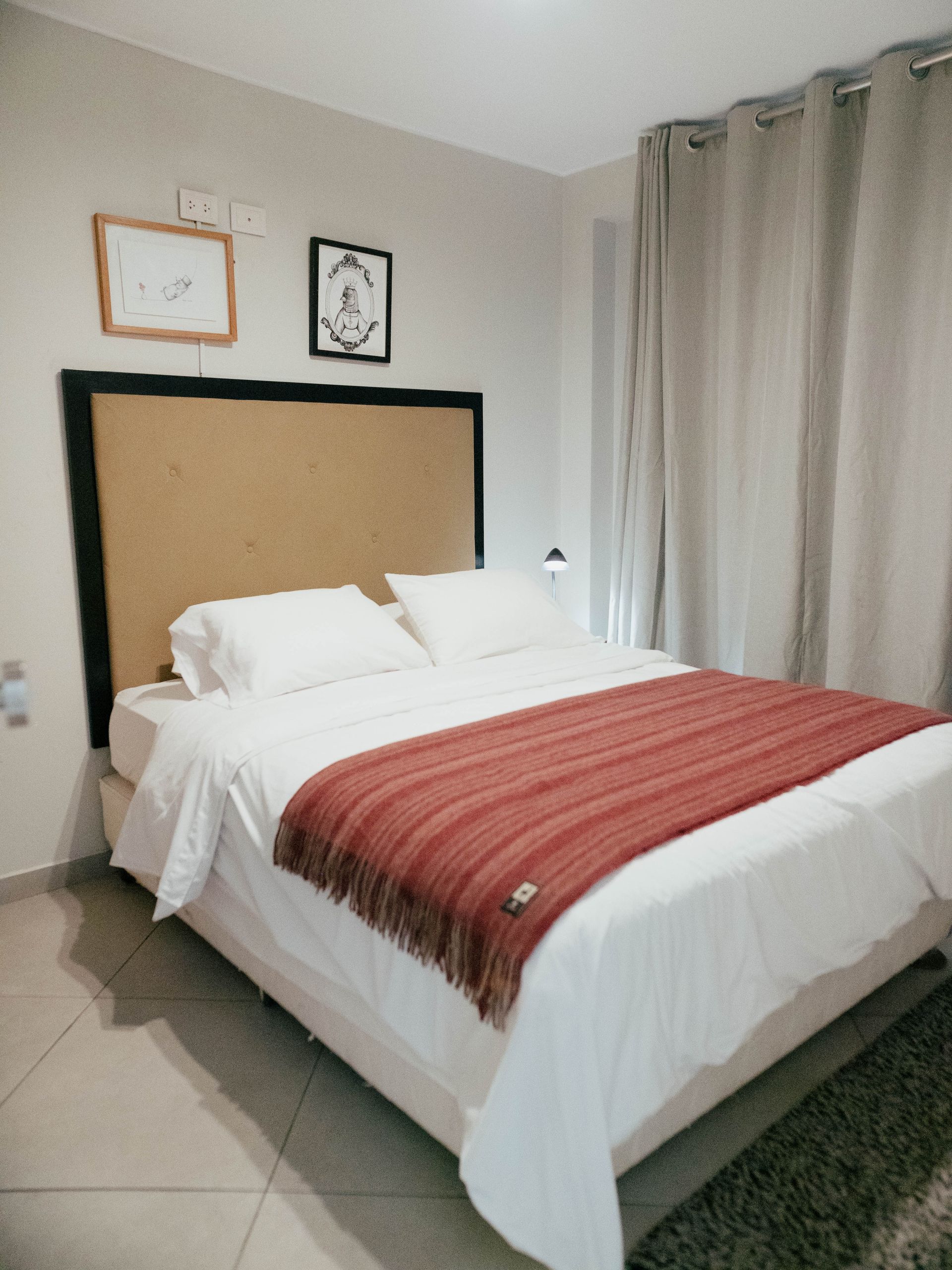 A bed with white sheets and a red blanket in a bedroom