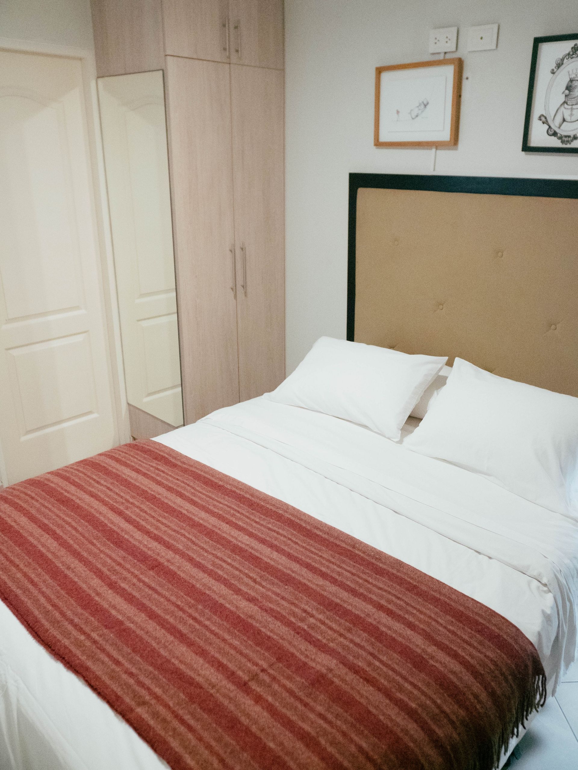 A bed with white sheets and a red blanket in a bedroom