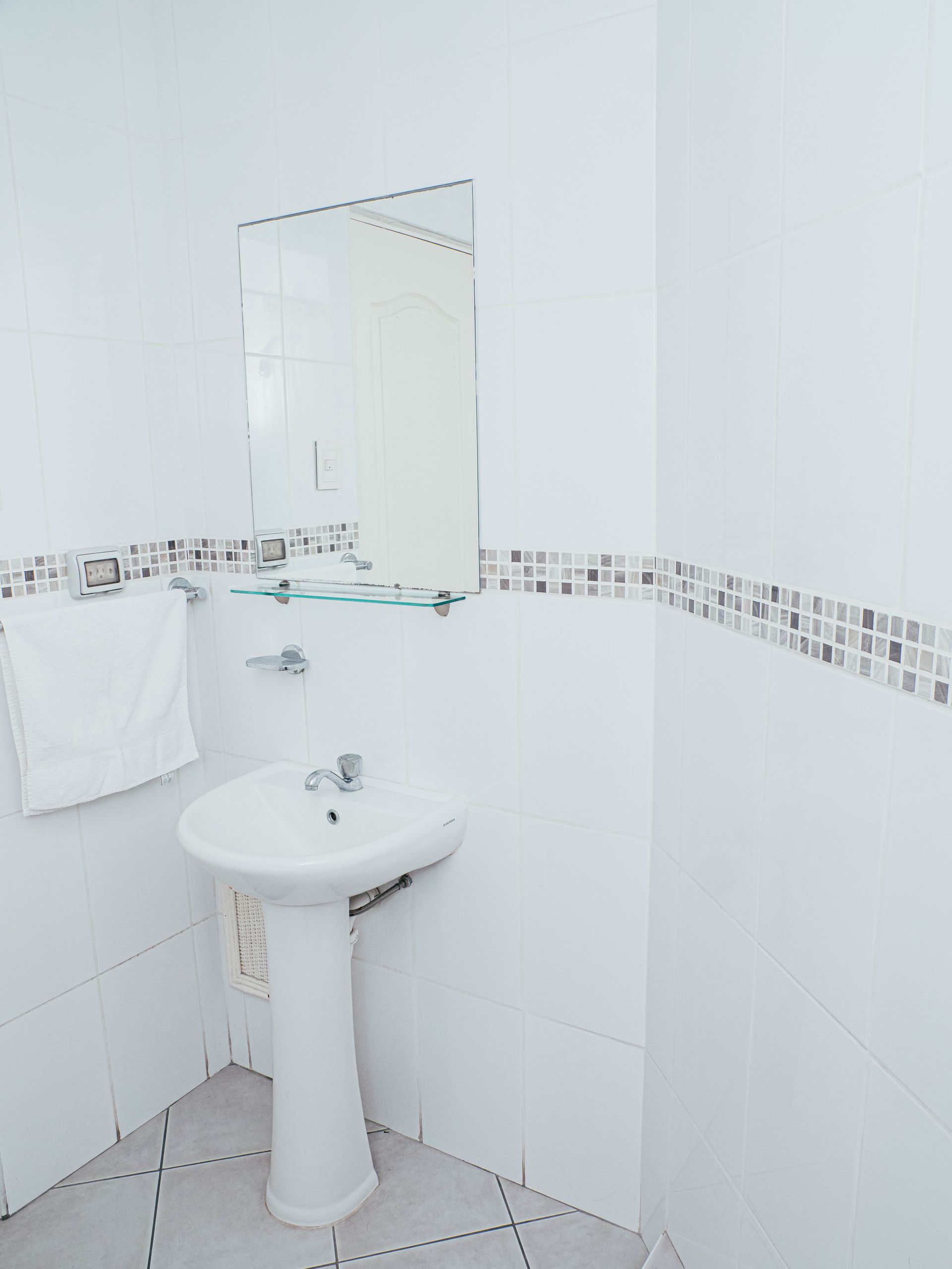 A bathroom with a sink , mirror and towel rack.