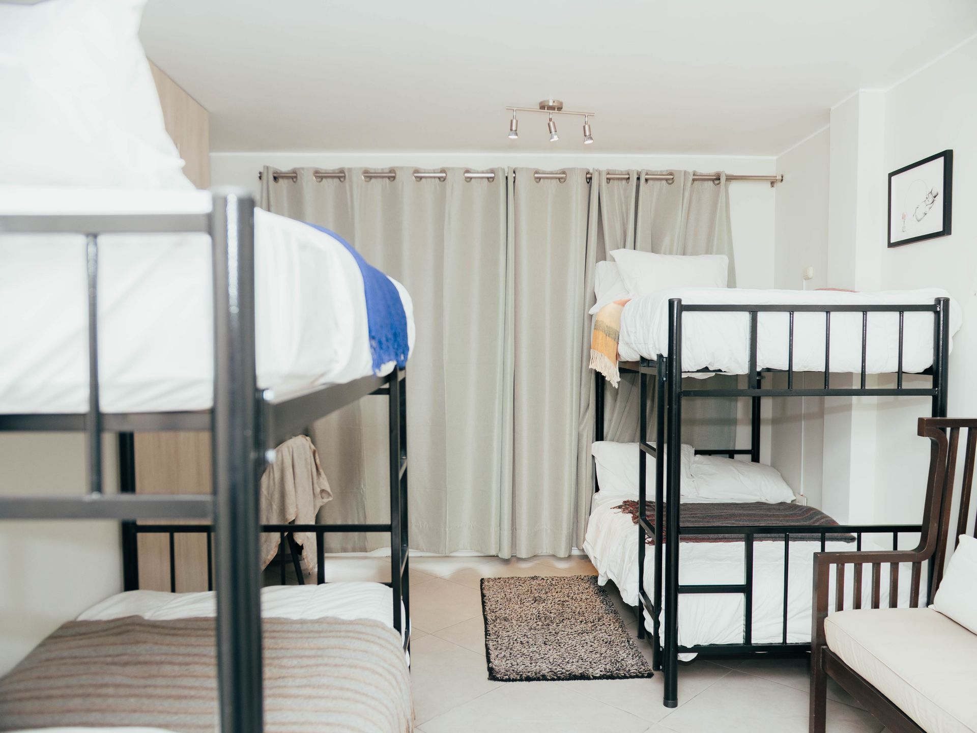 A room with four bunk beds and a chair.