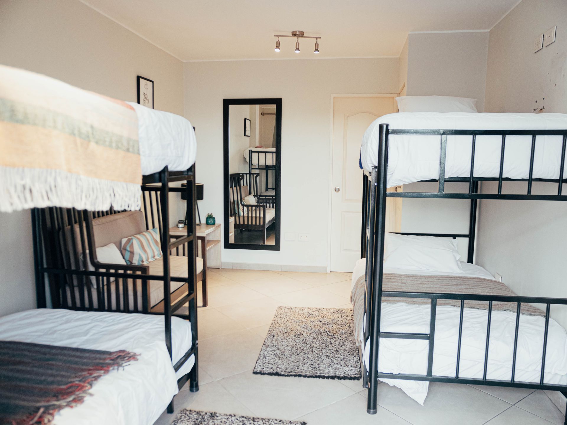 A bedroom with four bunk beds and a mirror.