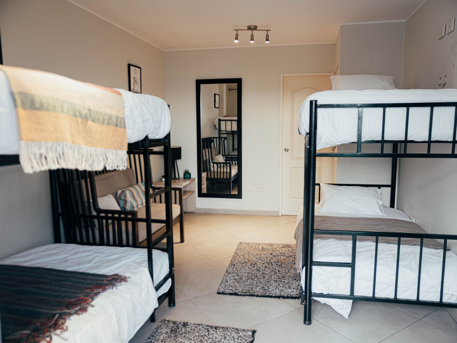 A bedroom with four bunk beds and a mirror.