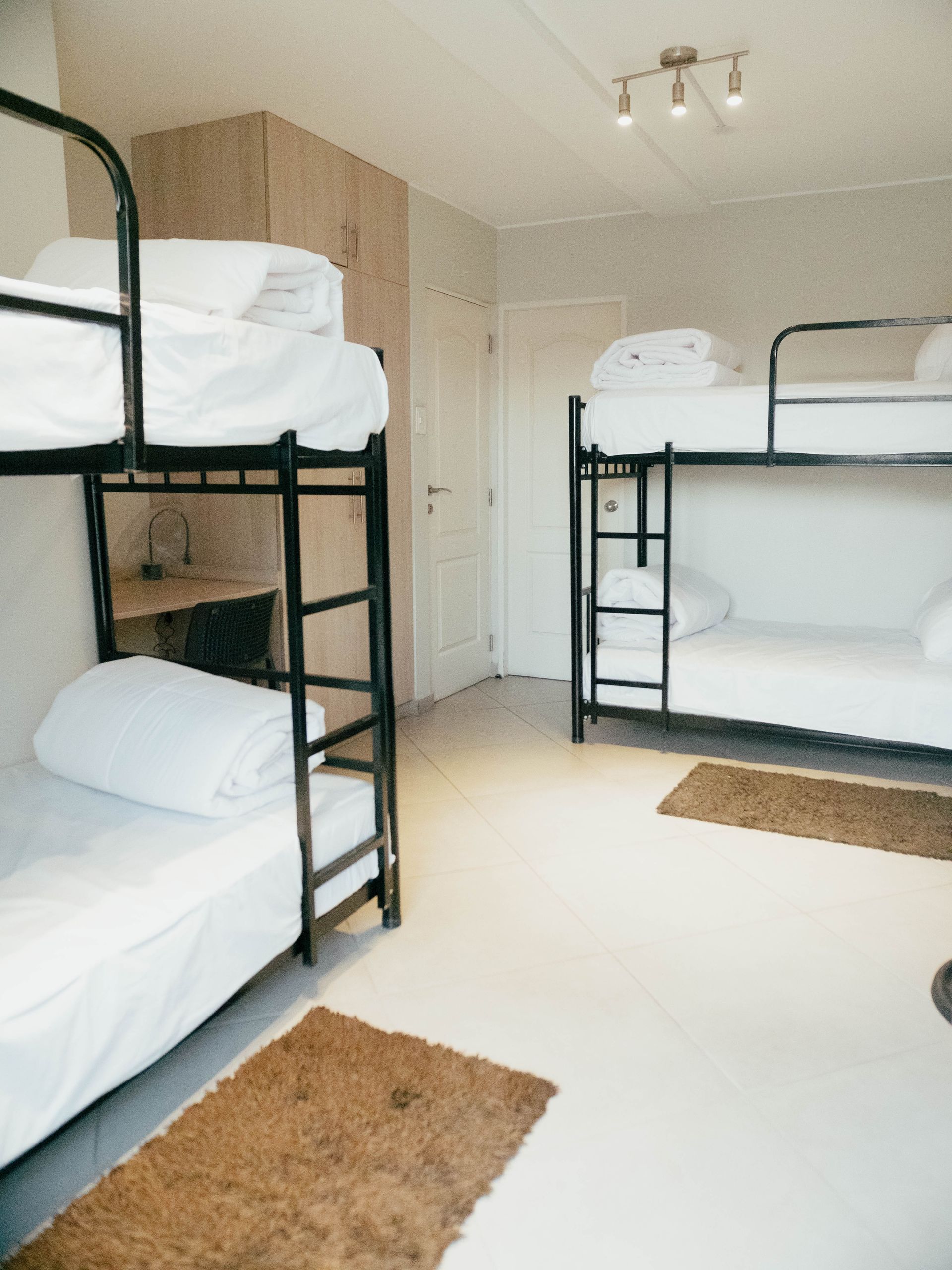 Three bunk beds in a room with white sheets