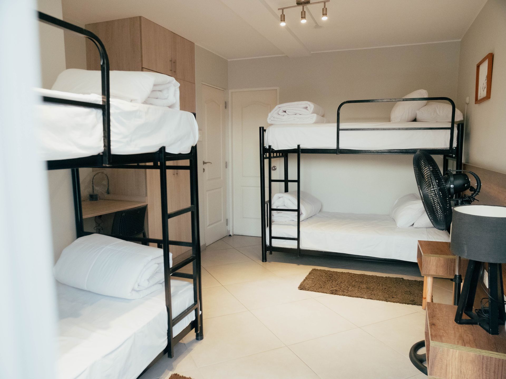 A bunk bed room with four bunk beds and a fan.