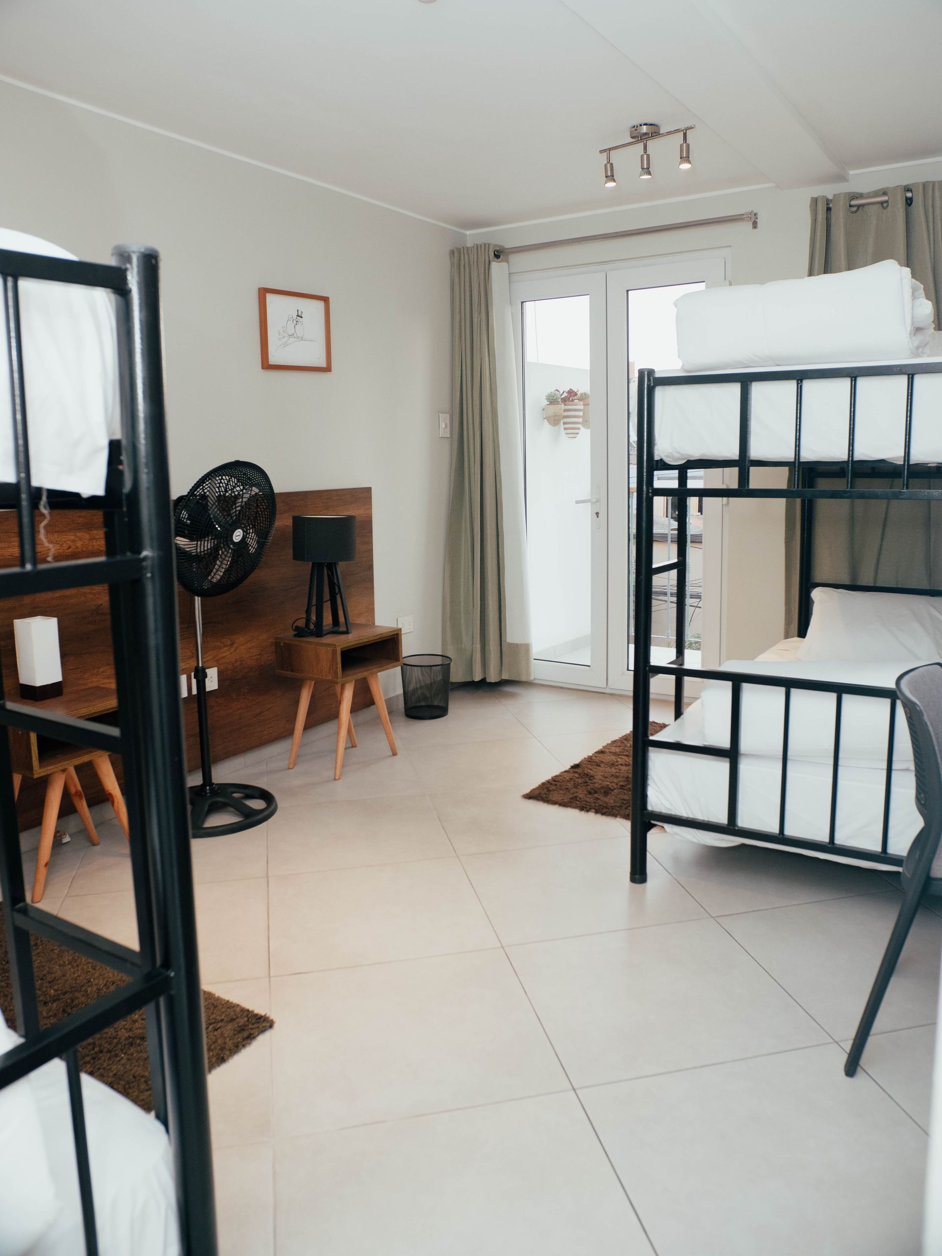 A room with two bunk beds and a fan