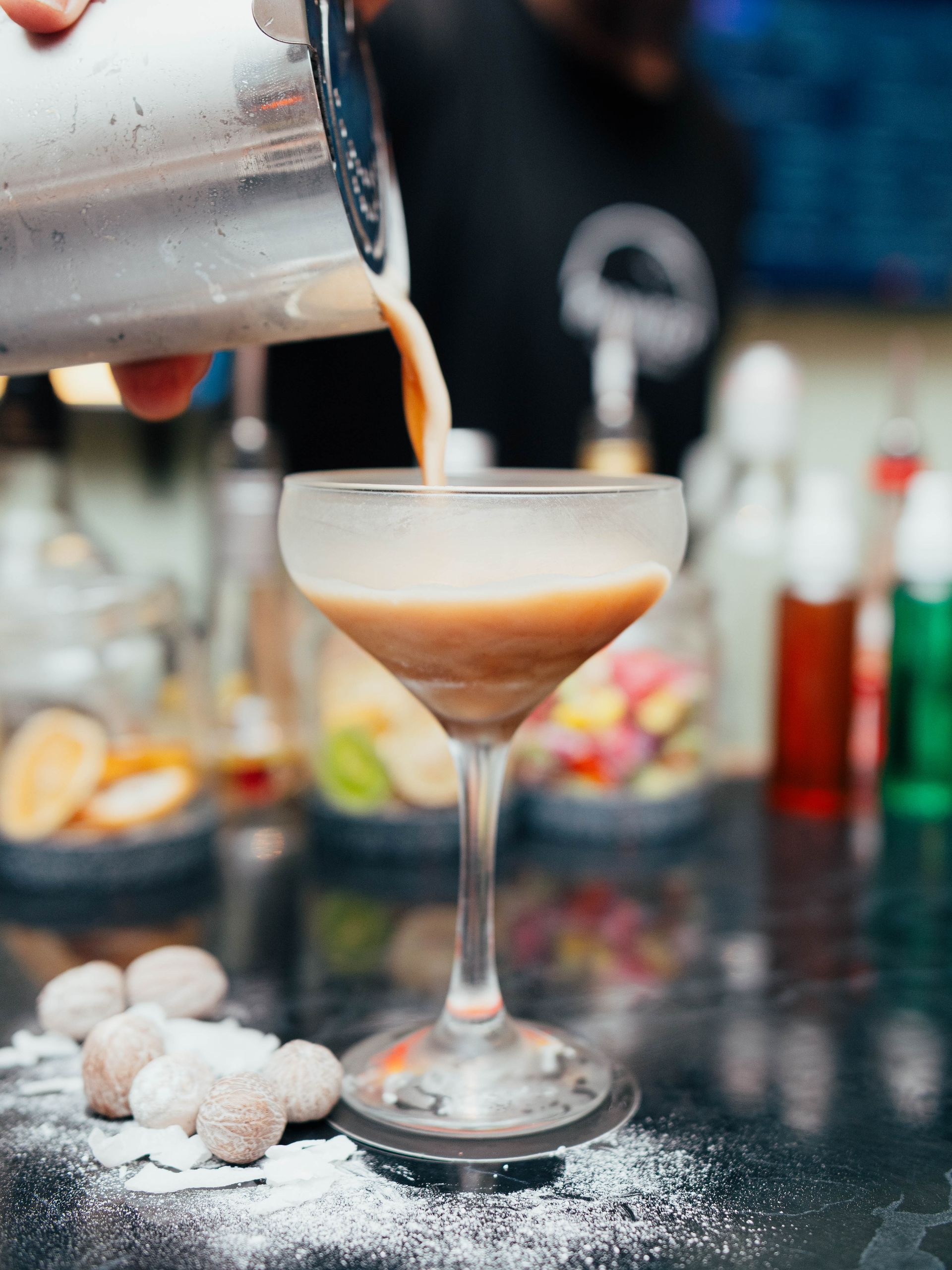 A bartender is pouring a drink into a martini glass.