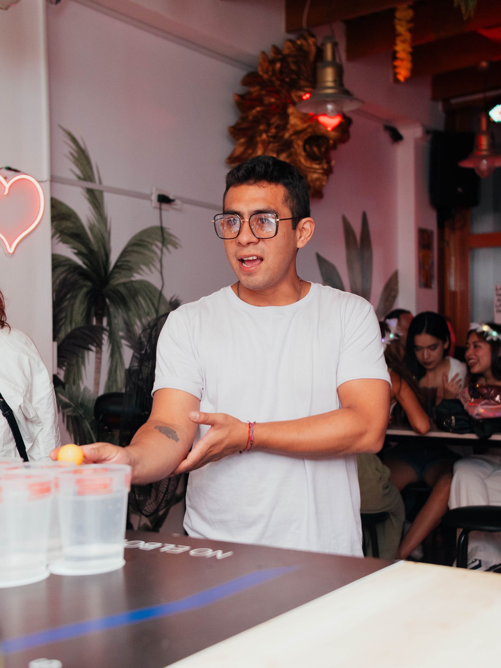 A man wearing glasses is standing in front of a table in a restaurant.