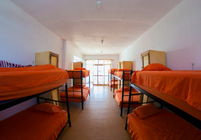 There are many bunk beds in this room with orange sheets.