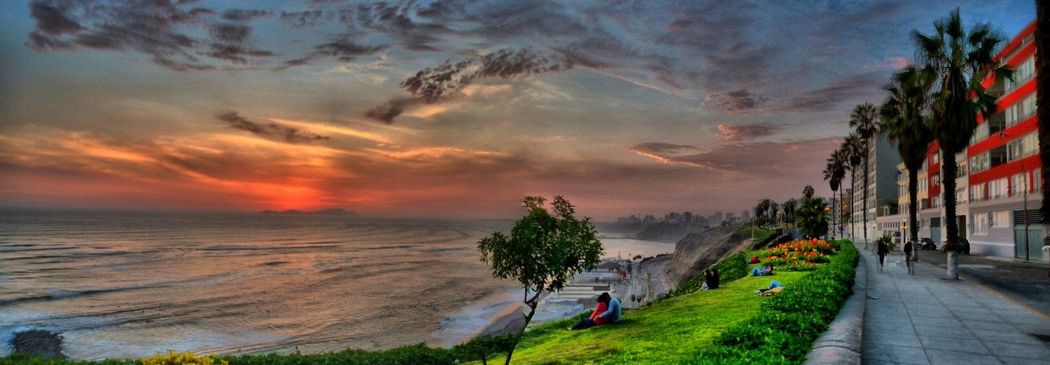 A sunset over the ocean with a sidewalk in the foreground.