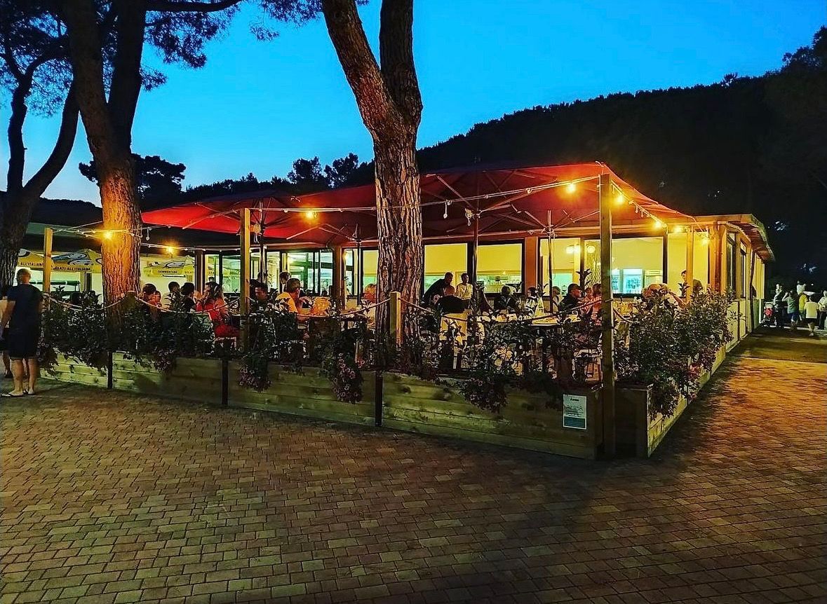Ristorante al tramonto con posti a sedere all'aperto, luci a ghirlanda e clienti.