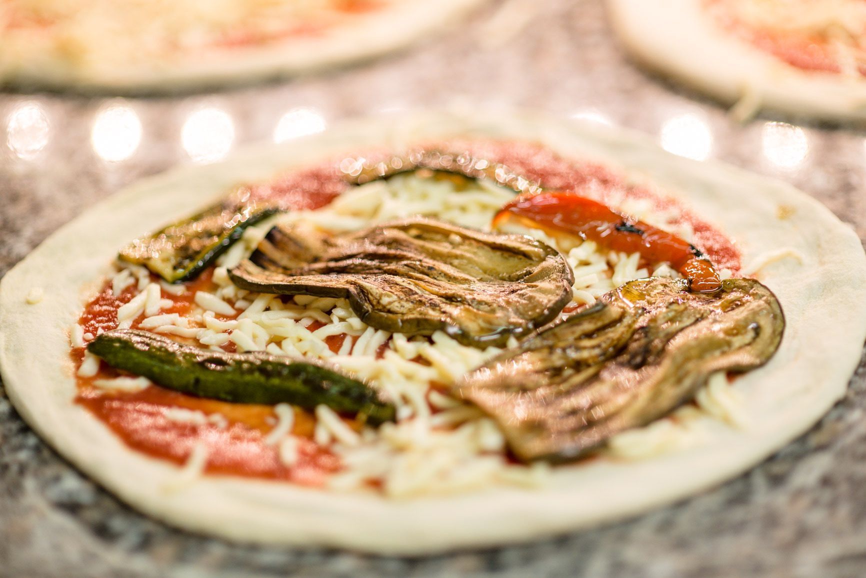 Base per pizza con salsa, formaggio e verdure grigliate.