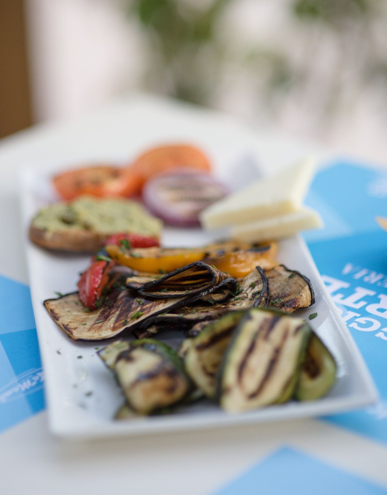 Verdure grigliate su un piatto rettangolare bianco, tra cui zucchine, melanzane, peperoni e pomodori.