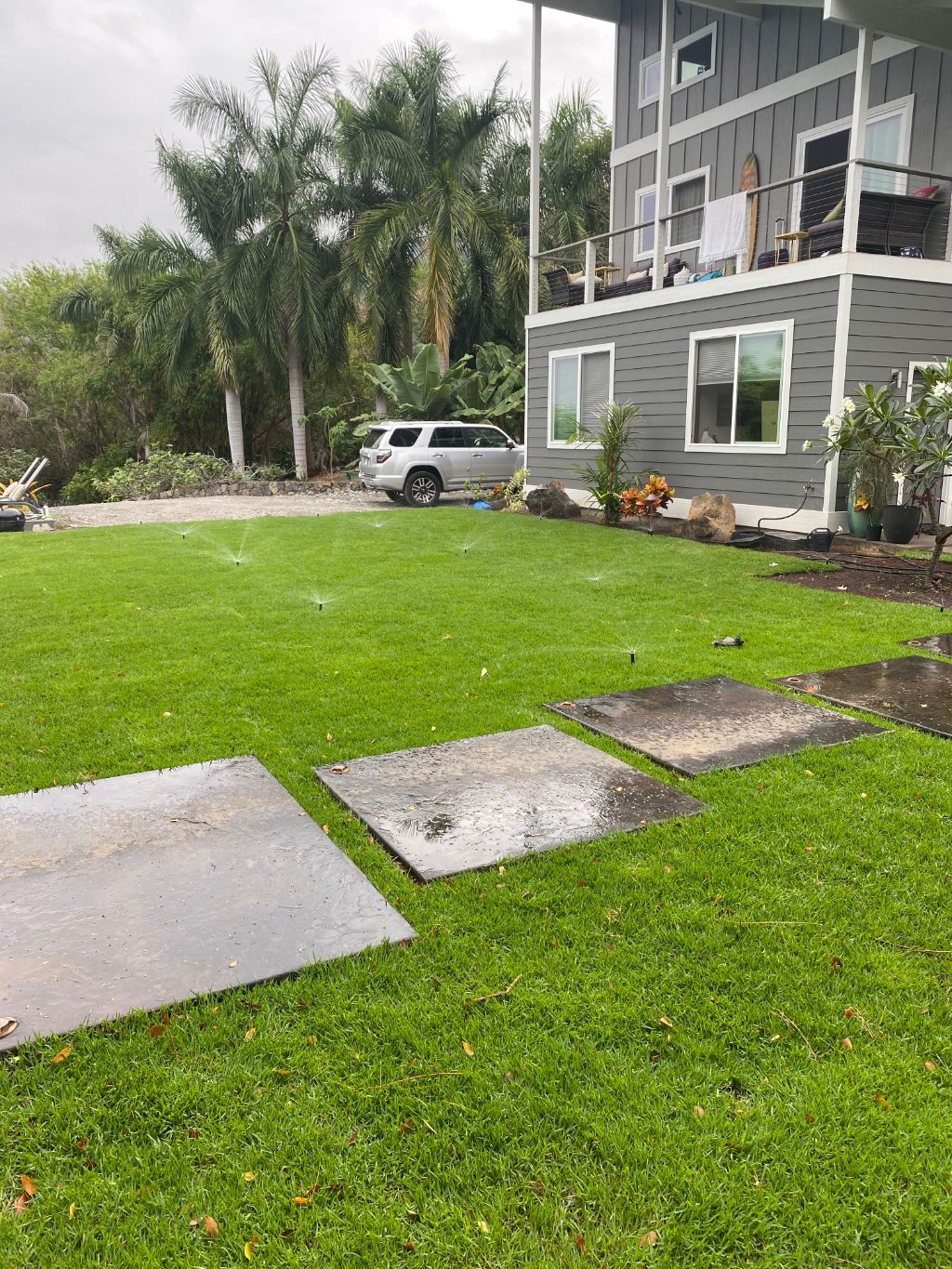 A large house with a lush green lawn in front of it with sprinklers on showing a sprinkler system installation prject. 