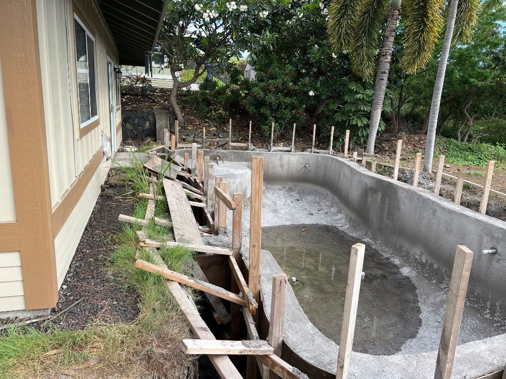 A swimming pool is being built in the backyard of a house.