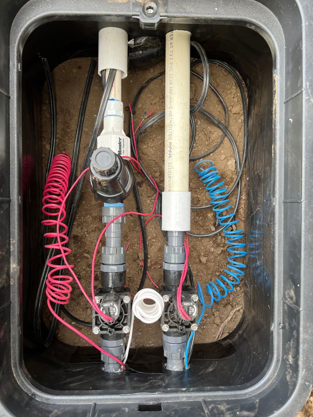 The inside of a sprinkler box with a bunch of wires coming out of it for sprinkler system installation. 