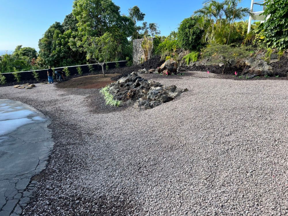 Grading and landscaping a gravel driveway with trees in the background
