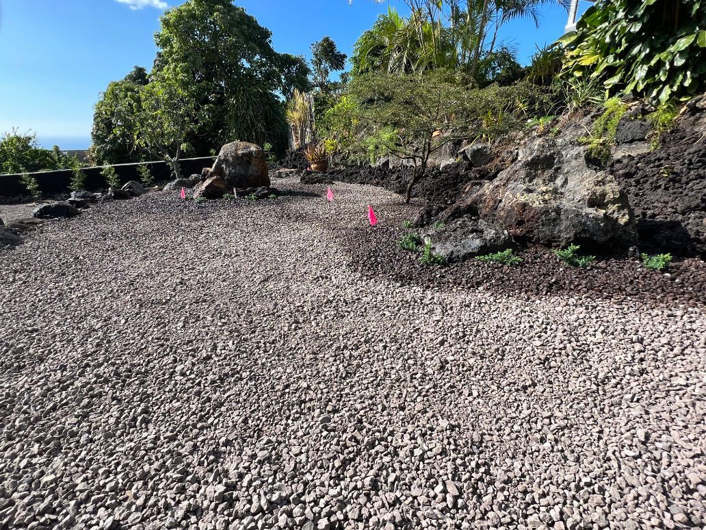 A gravel road surrounded by rocks and trees getting ready for grading and landscaping.