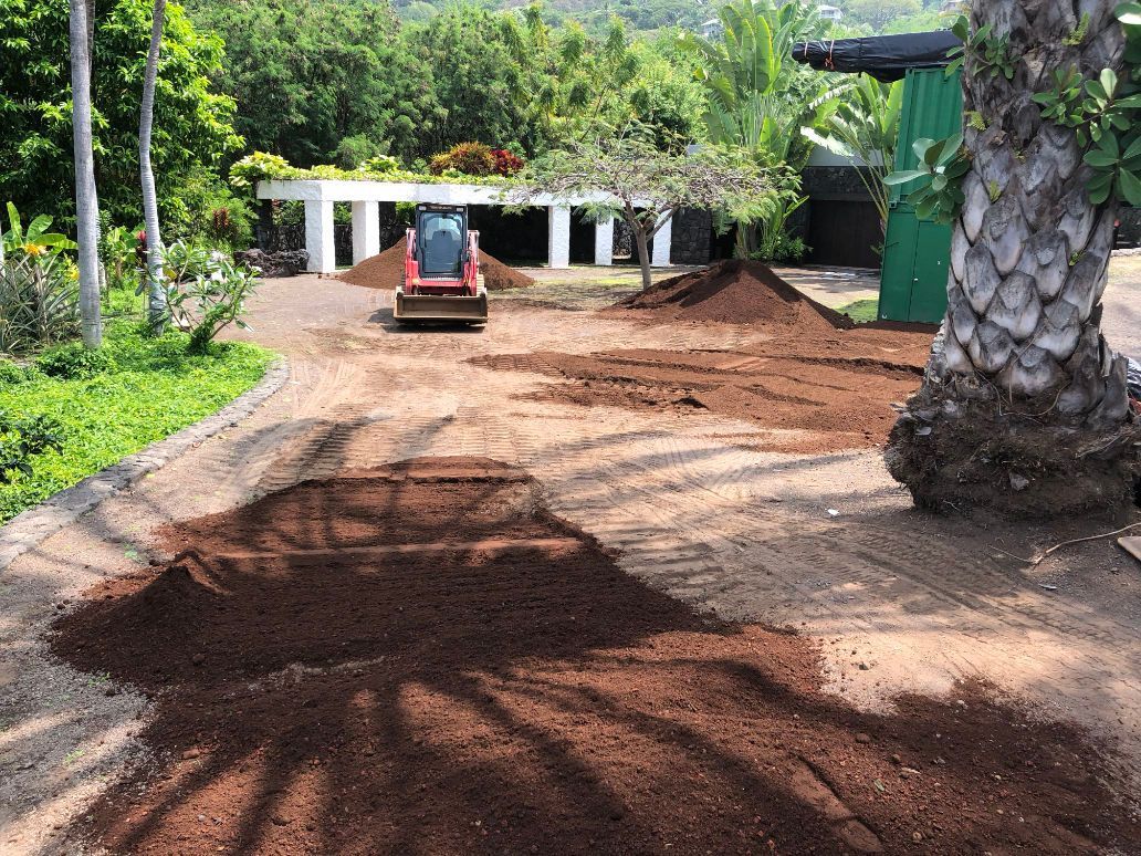 excavation and landscaping project showing a bulldozer is moving dirt in a driveway in front of a house.