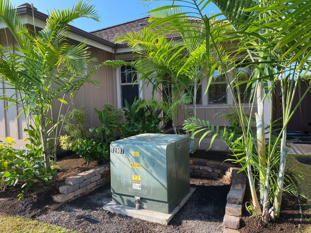 A green box is sitting in front of a house surrounded by trees showing a previous landscape installation project. 
