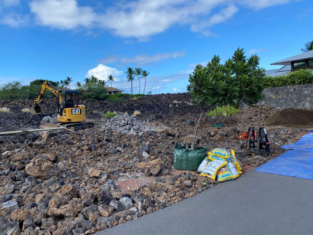 A construction site with a large pile of rocks and a yellow excavator doing excavation. 