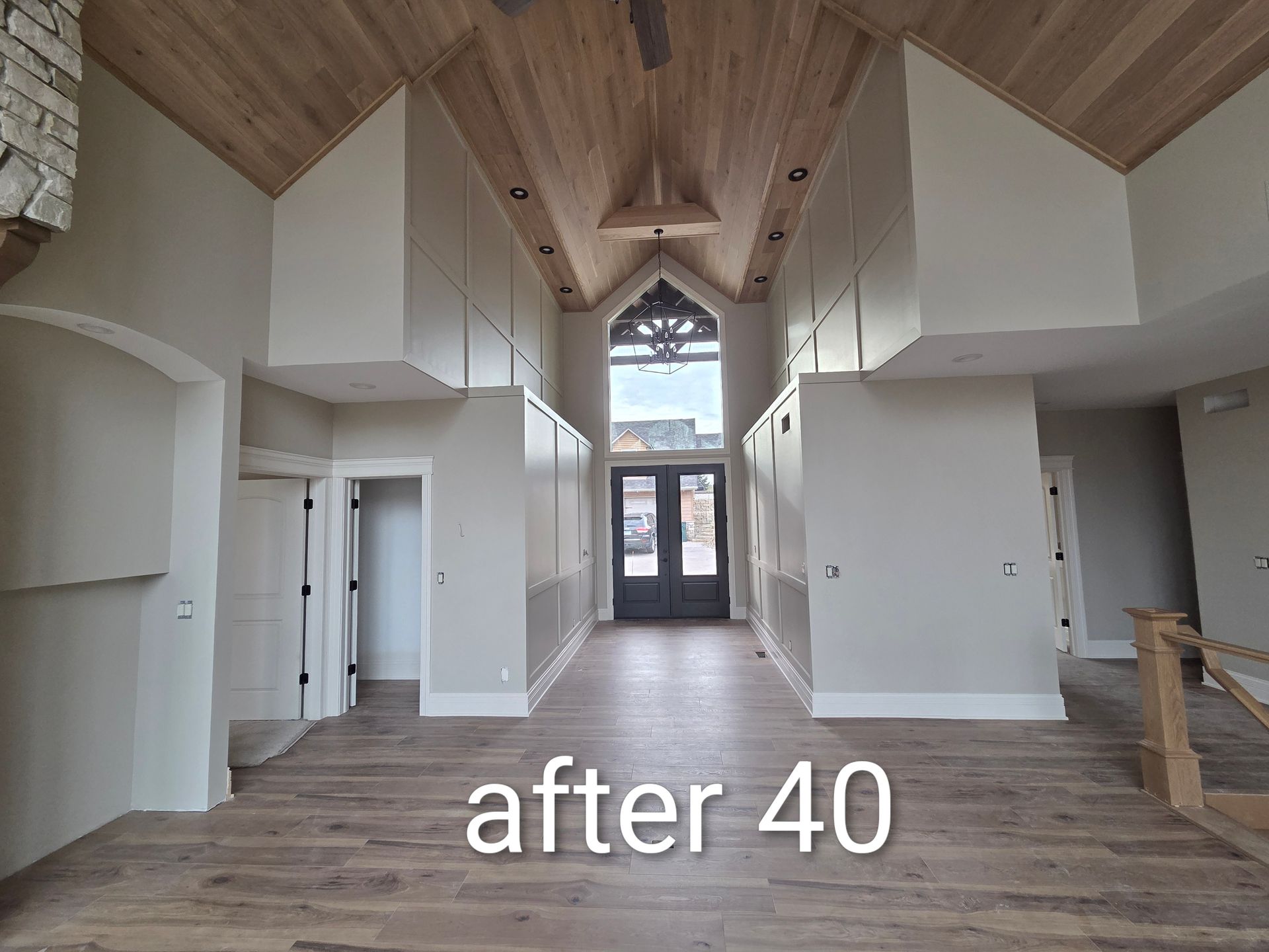 Renovated open room with vaulted wood ceiling, white walls, and large front windows, labeled “after 40”