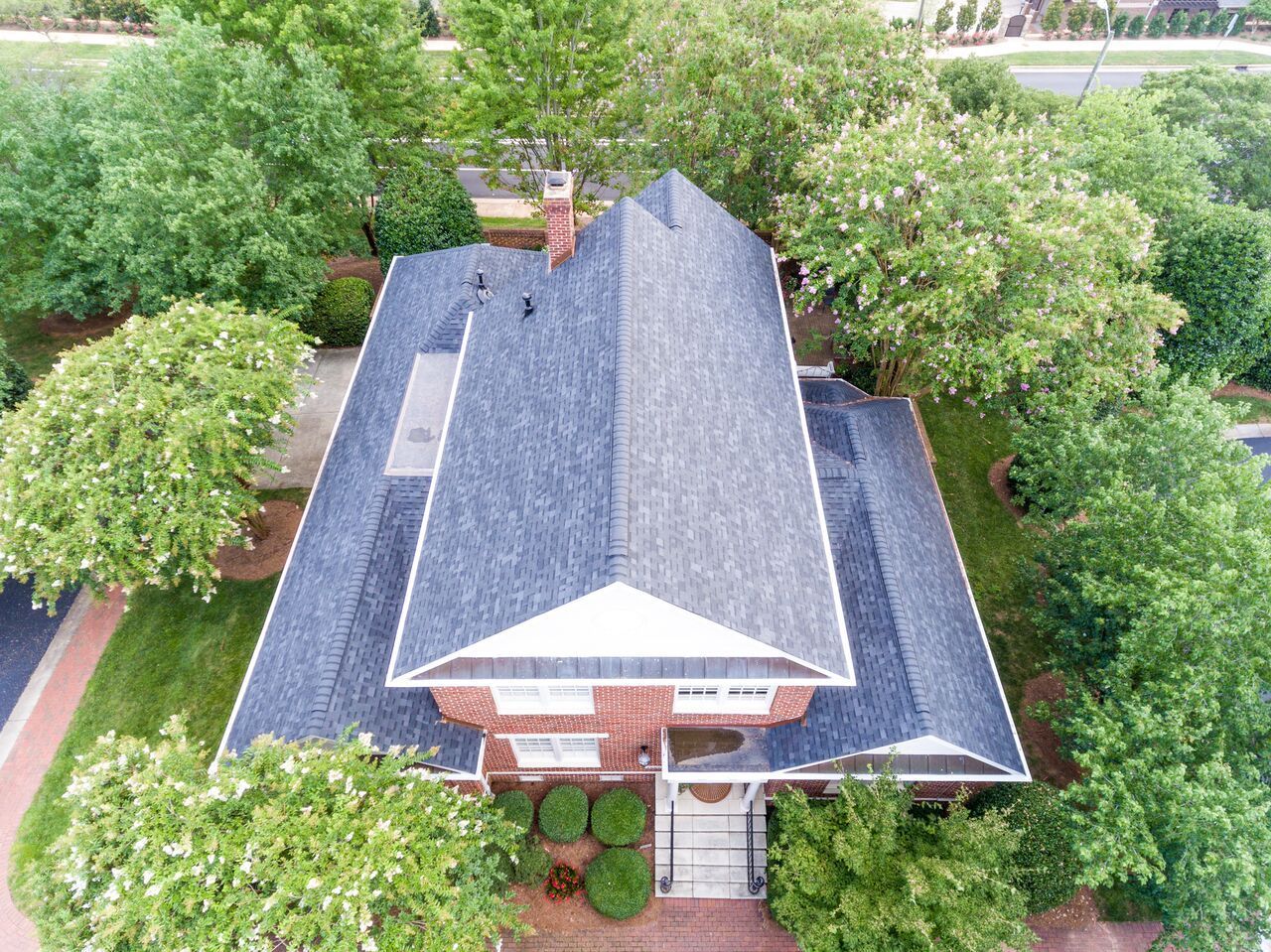 An aerial view of a large house with a blue roof surrounded by trees.