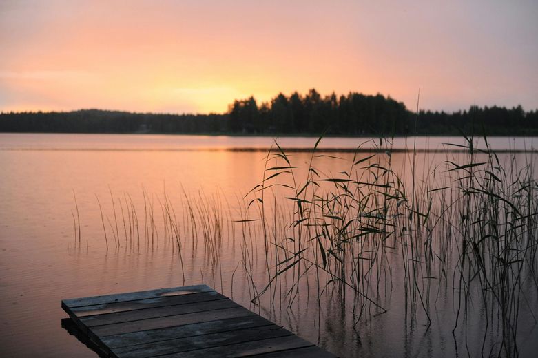 A sunset over a lake with a dock in the foreground