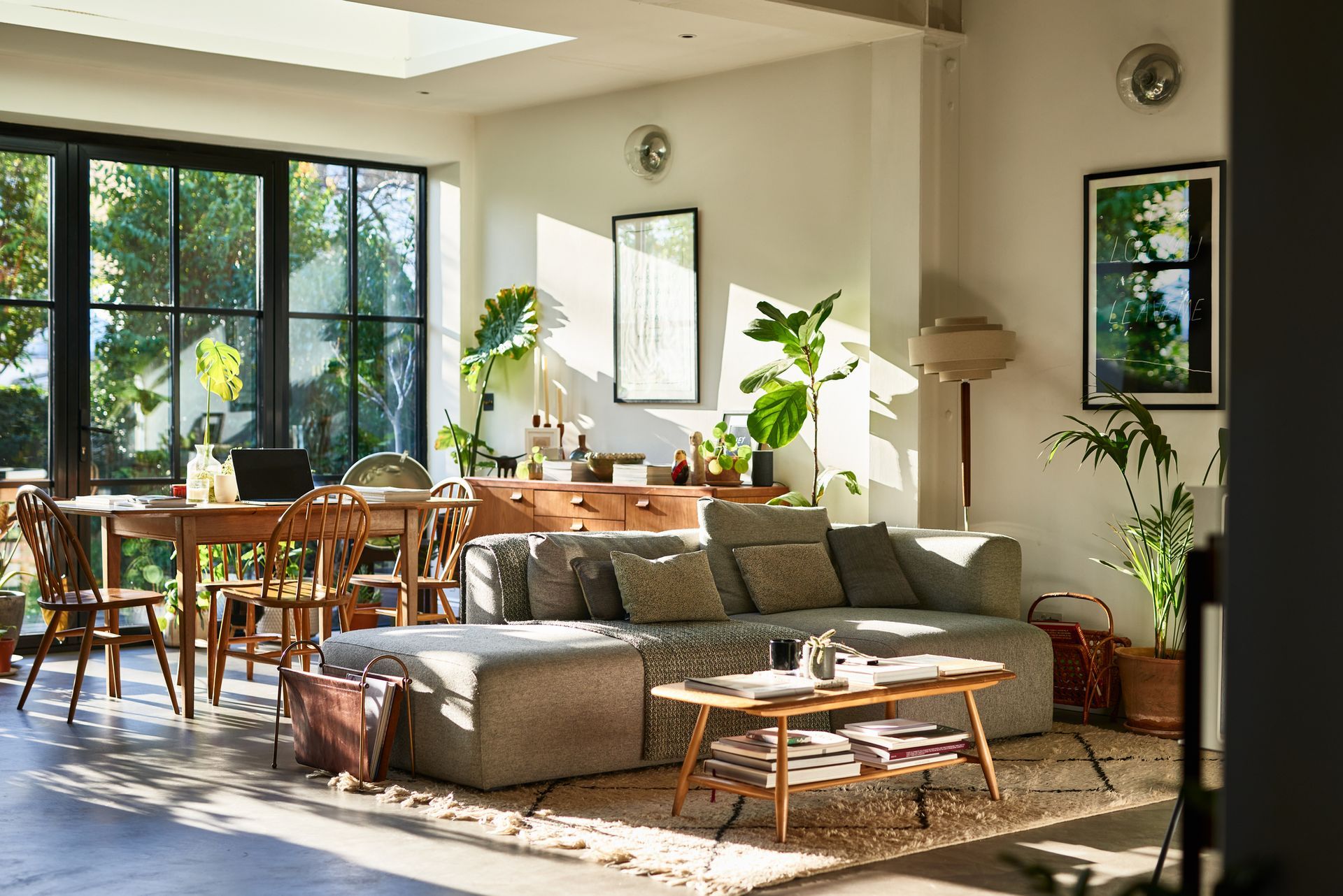 A living room with a couch , table , chairs and windows.