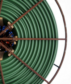 Two mechanics, in gray and red overalls, working on a car engine in a repair shop.