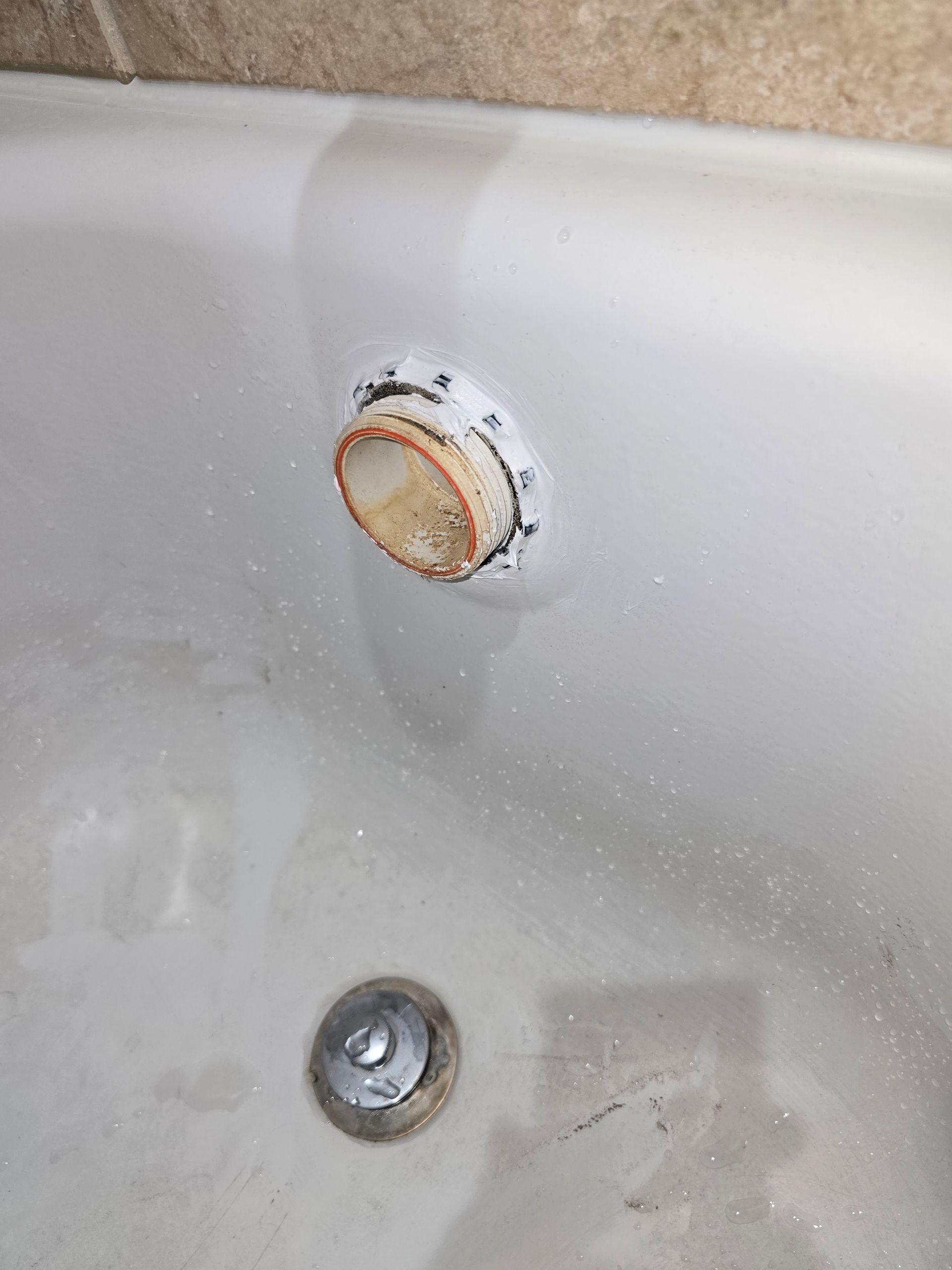White bathtub drain and overflow, with staining.