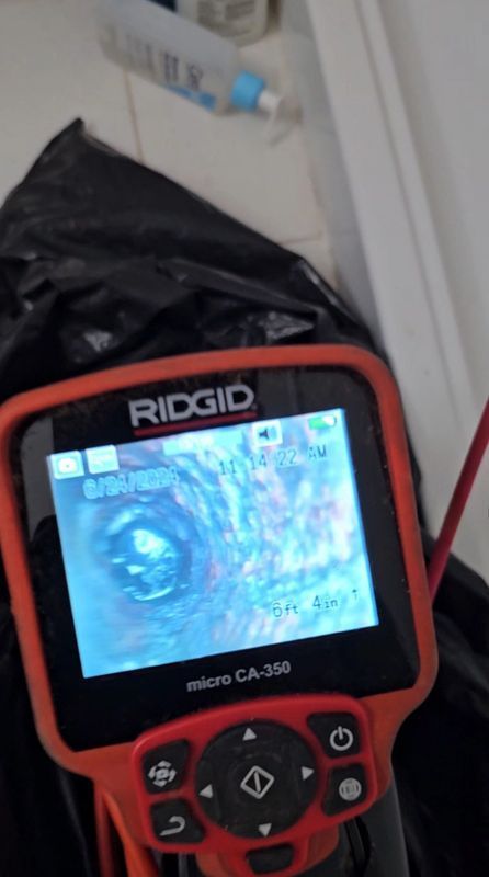 An orange Ridgid micro CA-350B inspection camera shows a dark interior. The camera displays a circular view.