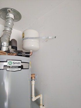 Water heater with expansion tank attached to a wall with metal tape.