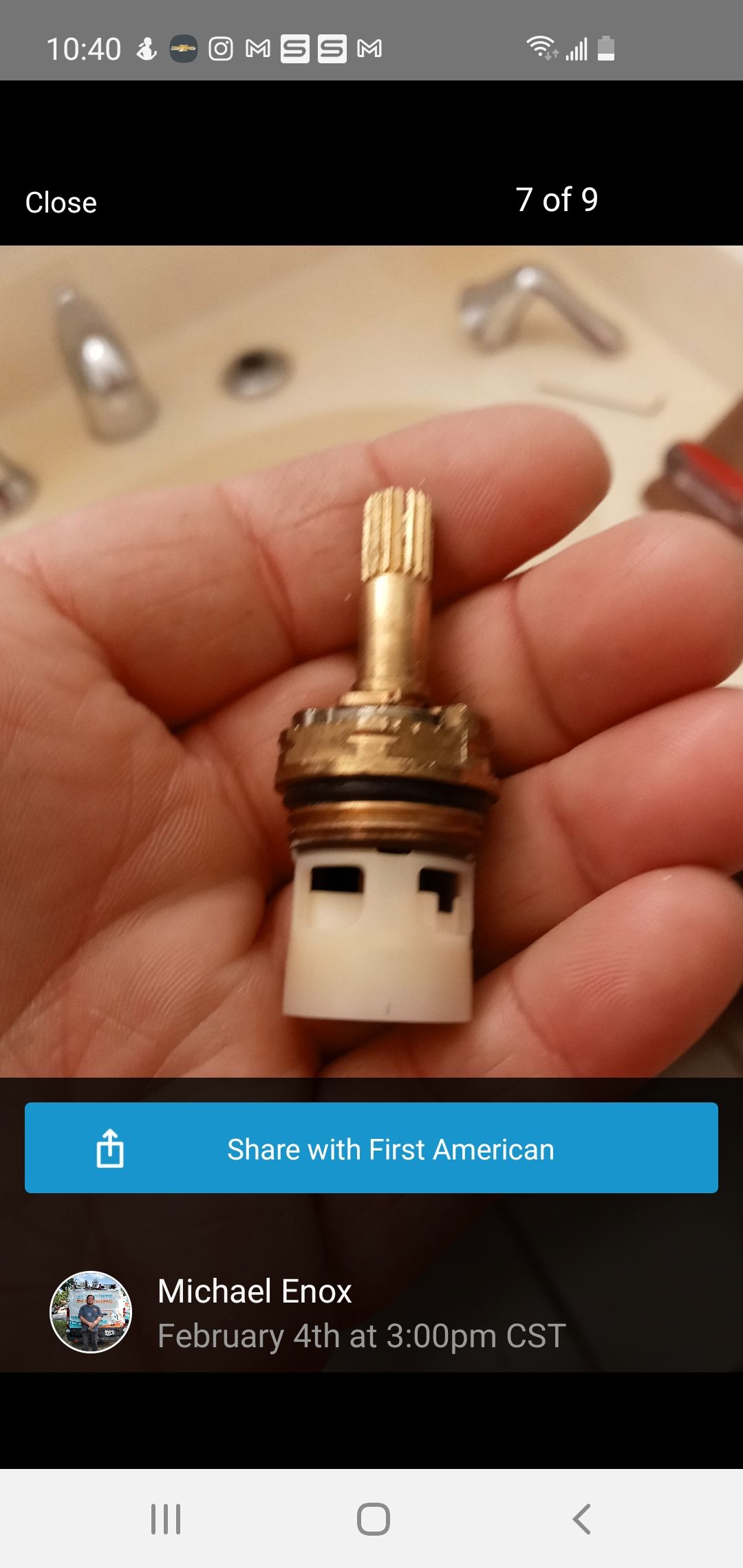 A person holds a brass faucet valve in their hand against a blurred background.