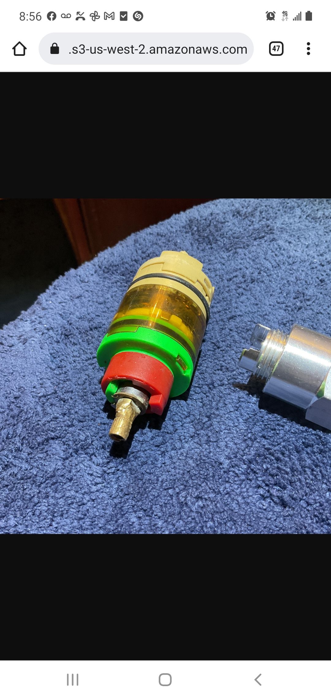 Close-up of a disassembled automotive part, with red, green, and gold components on a blue cloth.