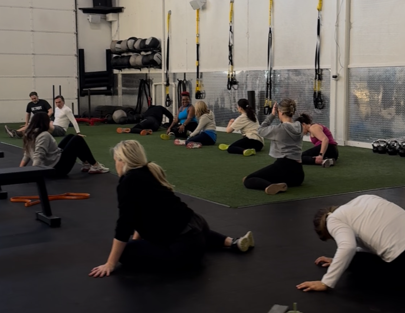 Group of young men in a gym, listening to someone in red shorts.