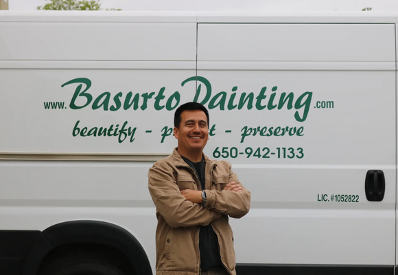 Nico Basurto standing in front of a Basurto Painting door carrier van.