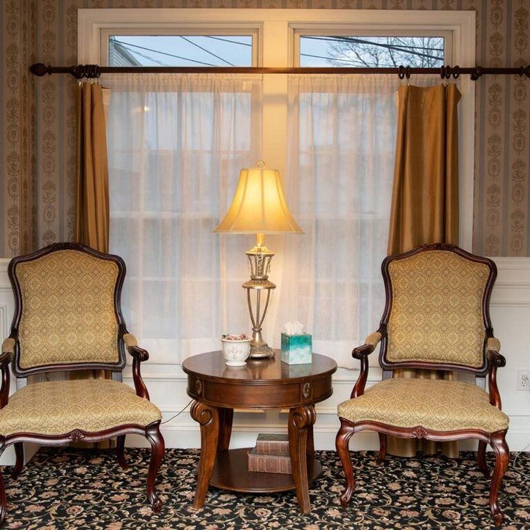 Two chairs and a table with a lamp in front of a window