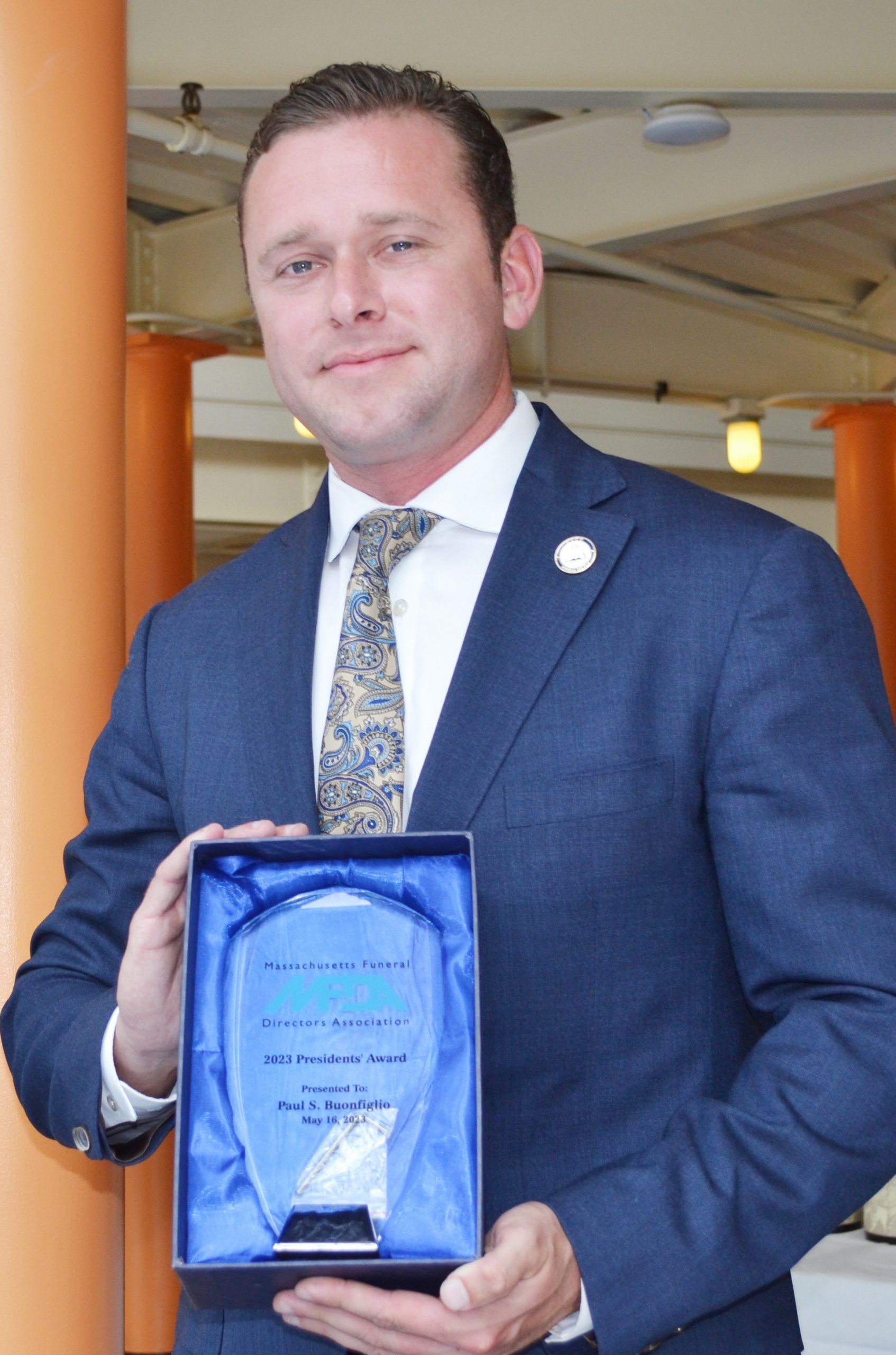 A man in a suit and tie is holding a plaque