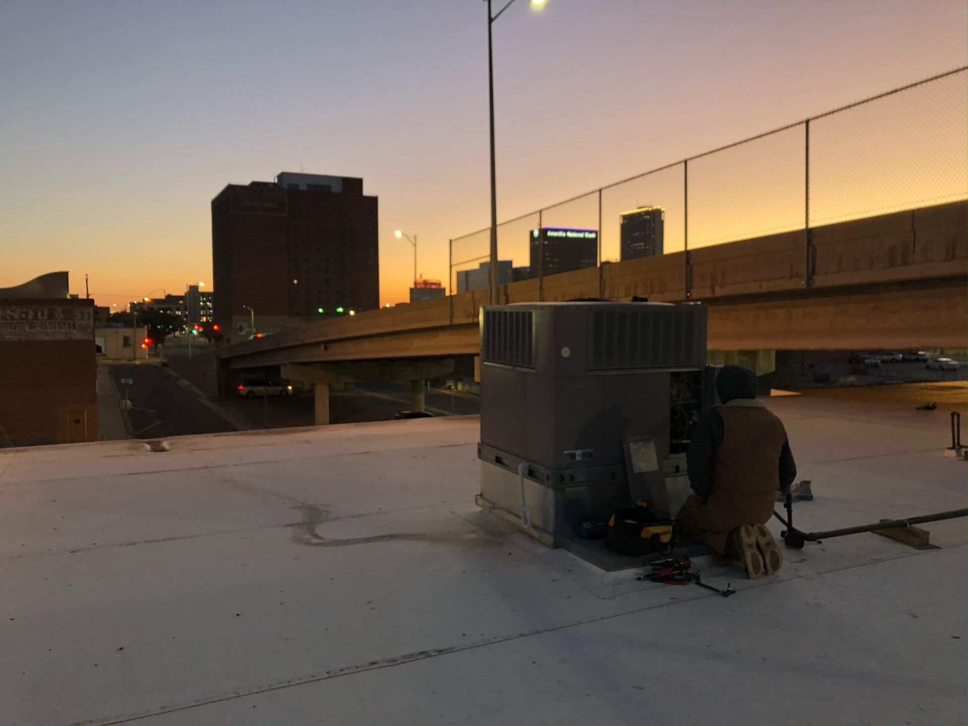 A man is working on a roof at sunset.