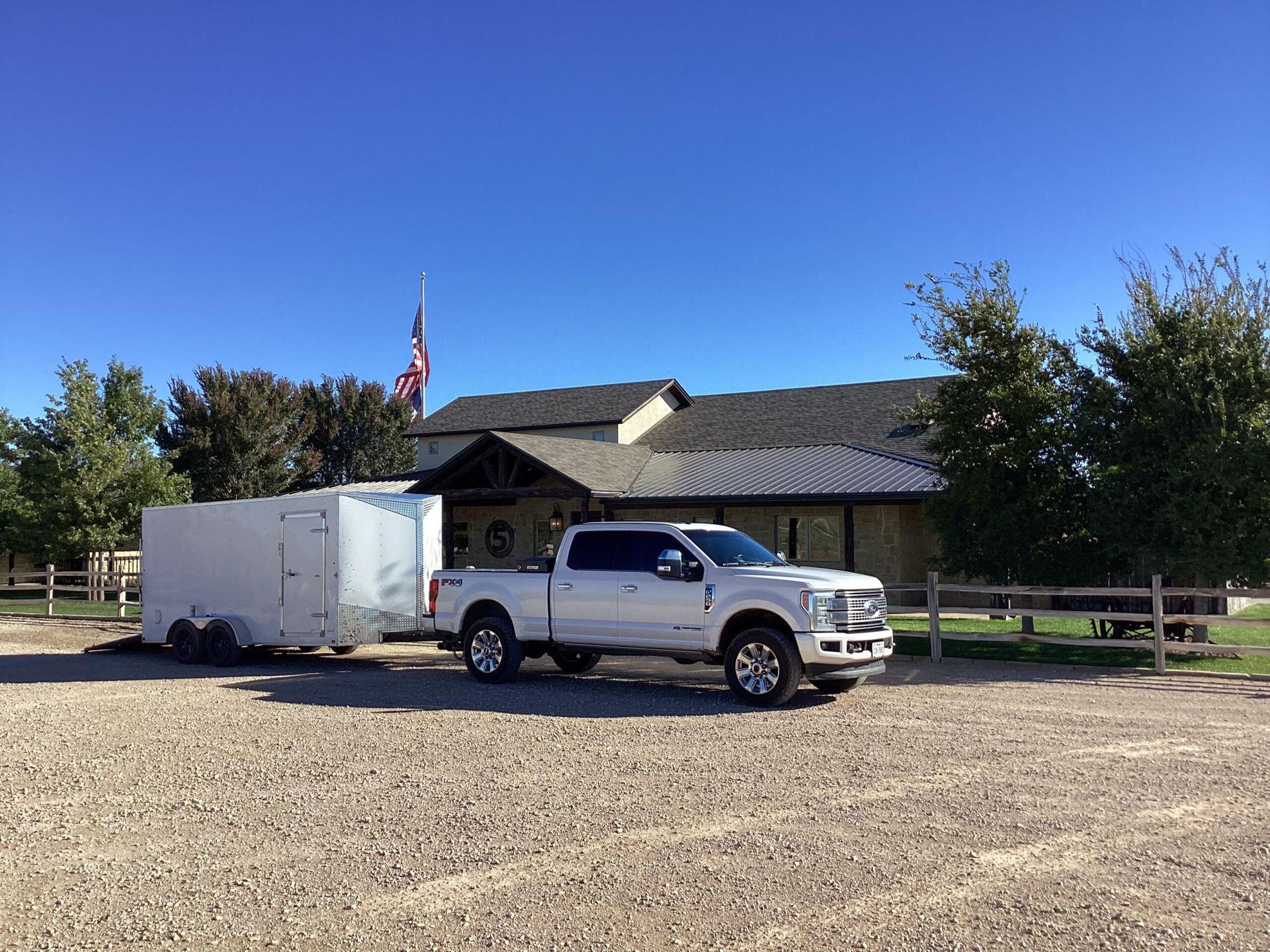 A white truck with a trailer attached to it is parked in front of a house.