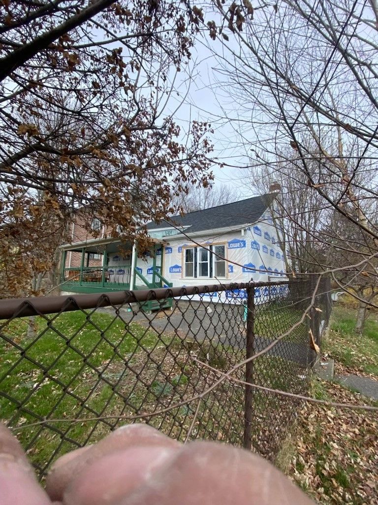 A person is holding a chain link fence in front of a house.  - Kingston, NY - JMD Home Improvements