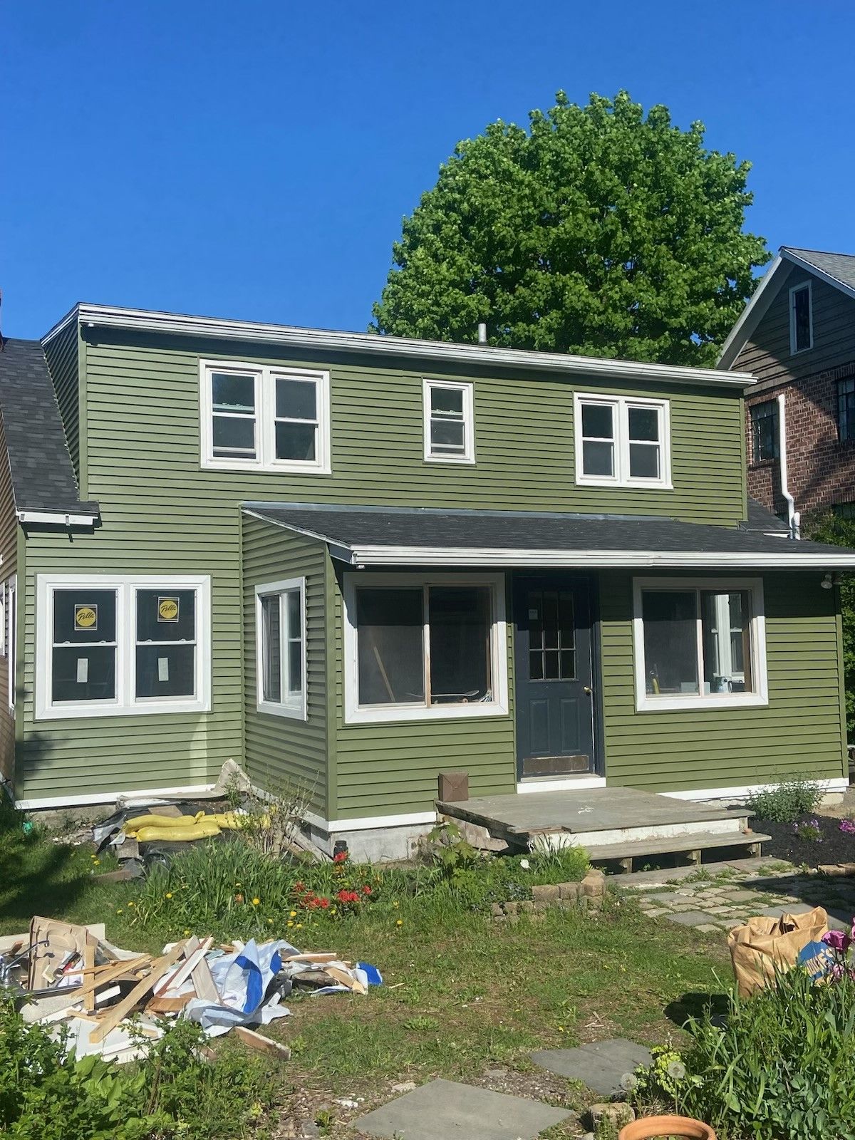 A green house with white windows and a black roof  - Kingston, NY - JMD Home Improvements