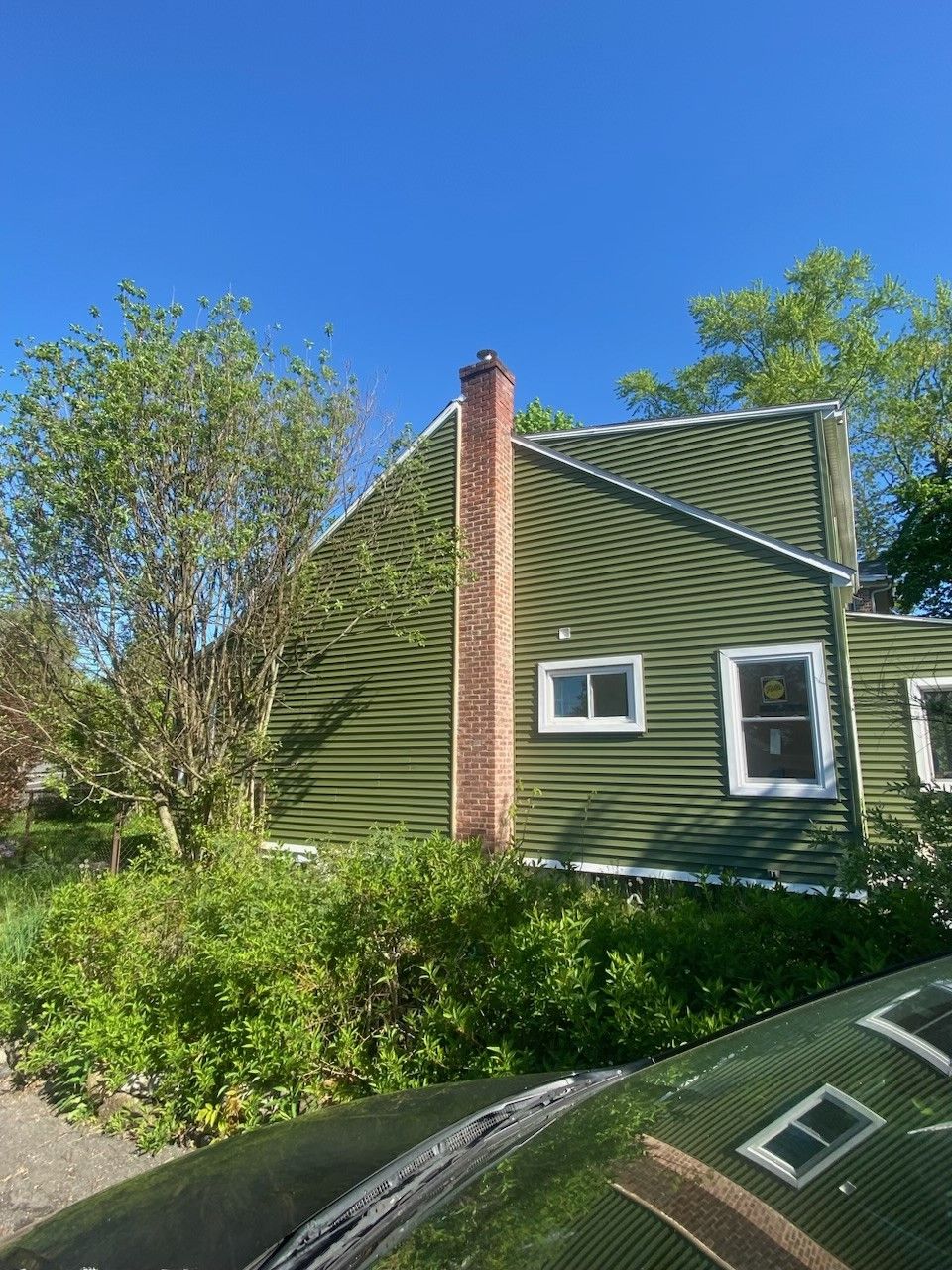 A green house with a chimney and a car parked in front of it.  - Kingston, NY - JMD Home Improvements