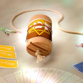 Dreidel de madera con cuerda, cartas y fondo decorativo.