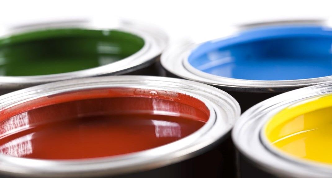 Four cans of paint of different colors and paint finish are stacked on top of each other.