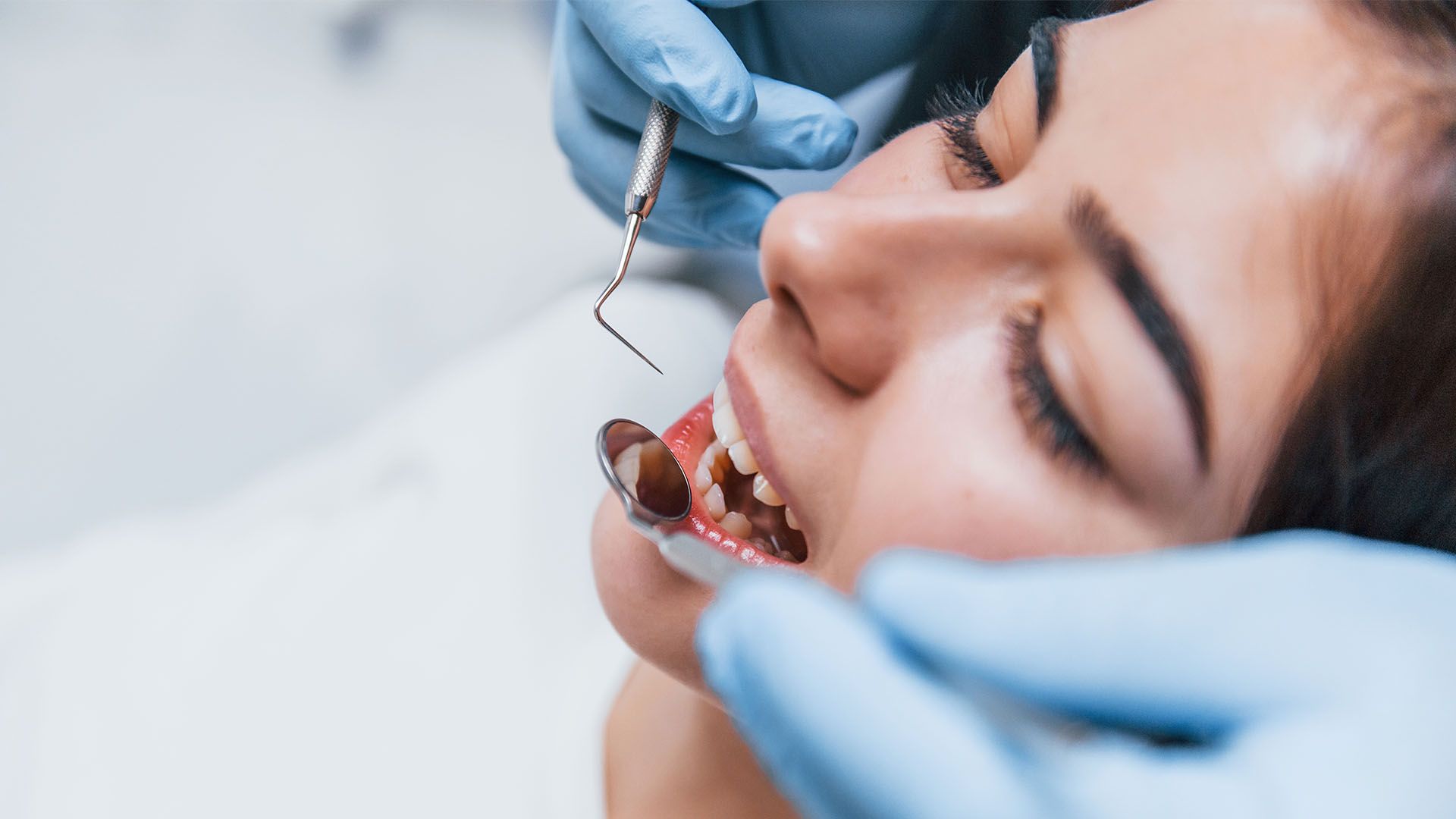 A woman is getting her teeth examined by a dentist.