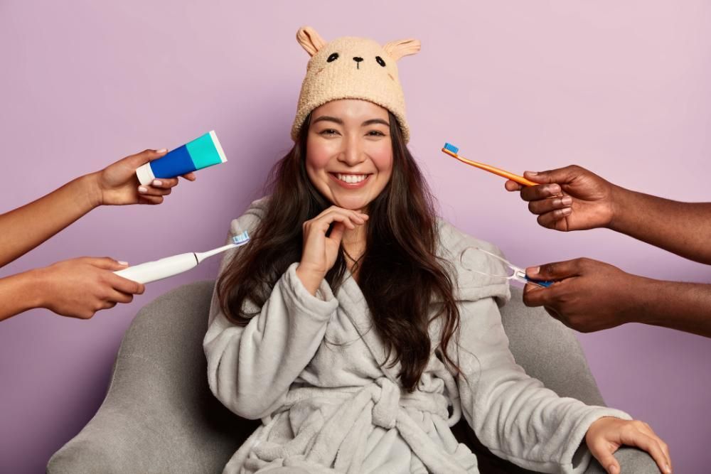 A woman is sitting in a chair surrounded by people holding toothbrushes and toothpaste.