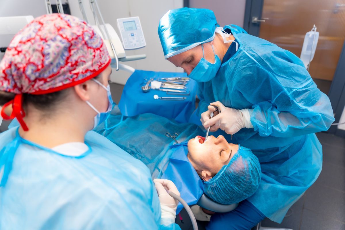 Two dentists are examining a patient 's teeth in a dental office.