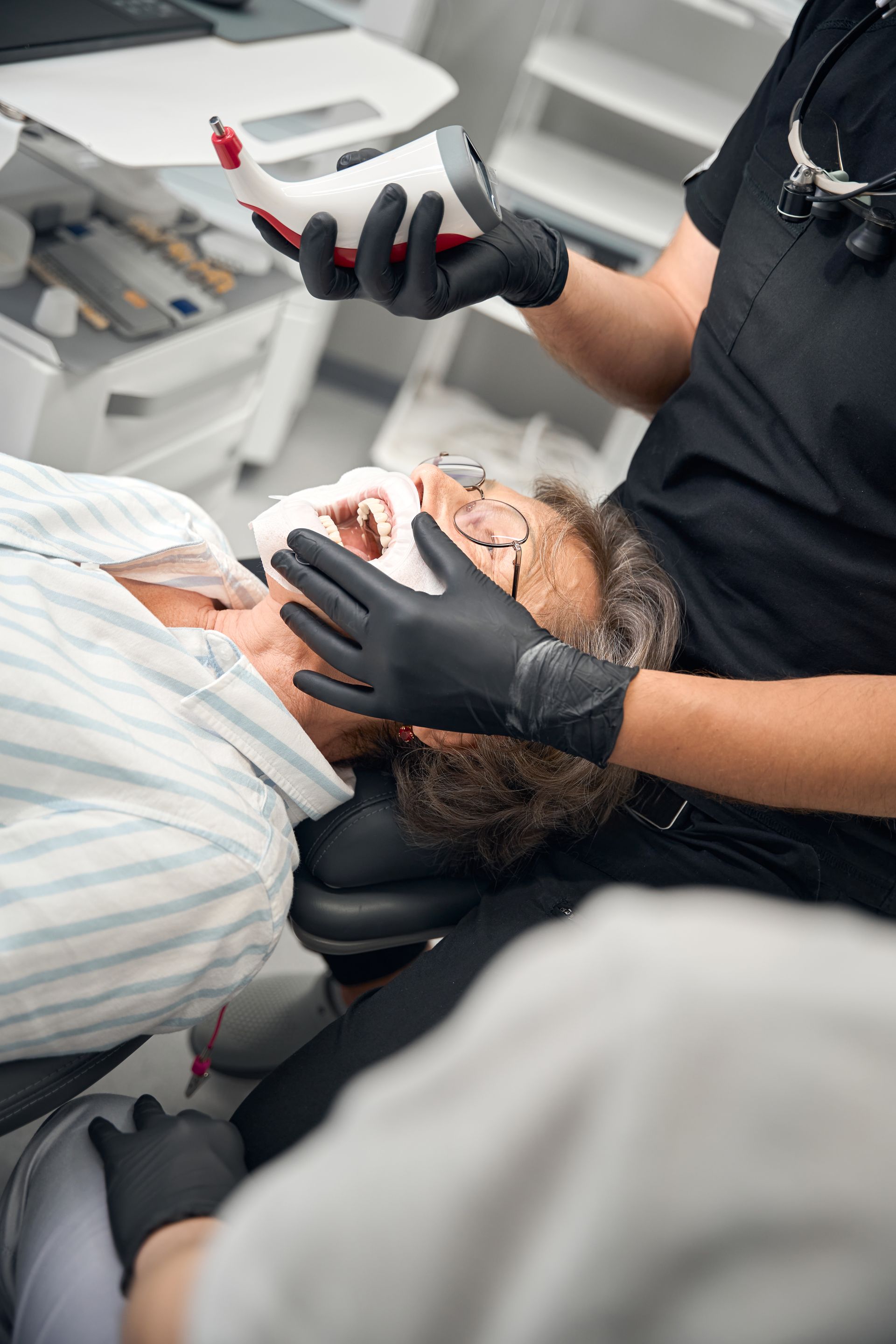Dentist examining a patient in a dental chair with gloves and a mouth mirror